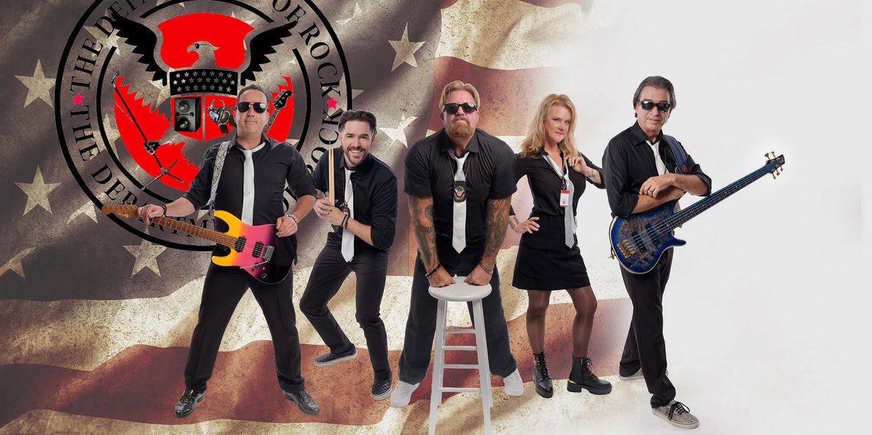 Five musicians posing with instruments and an American flag background.