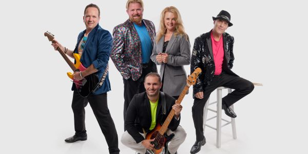 Group of five musicians posing with guitars and smiles.