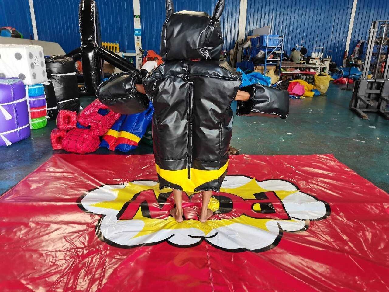 Person in an inflatable black and yellow costume standing on a red mat with comic text.