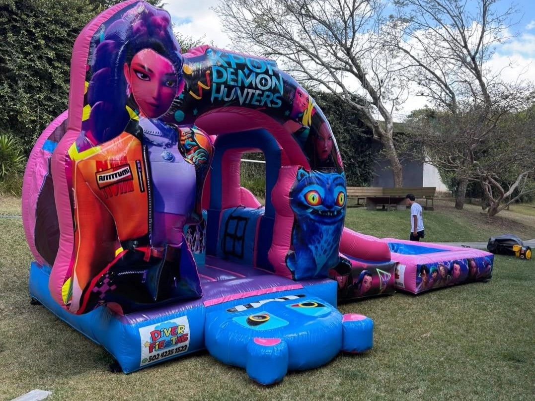 Colorful K-Pop Demon Hunters inflatable bounce house with cartoon characters on a grassy lawn.