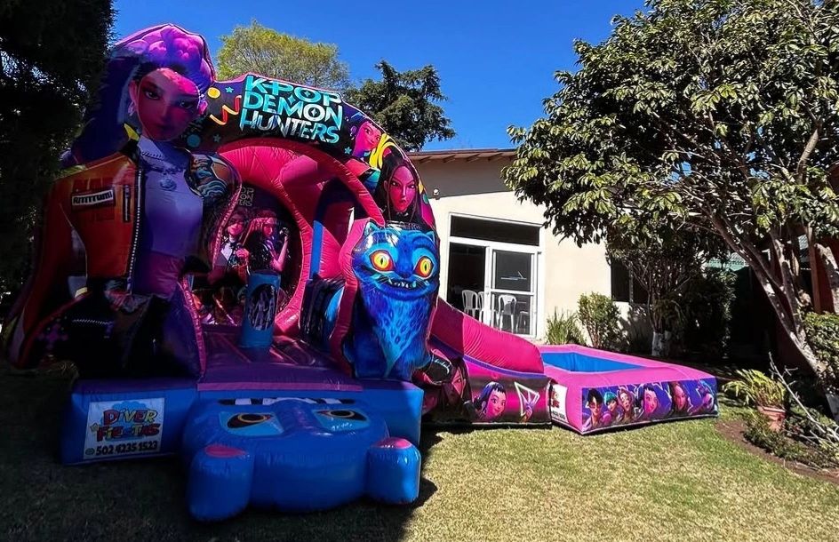 Colorful K-pop Demon Hunters inflatable bounce house in a sunny backyard.