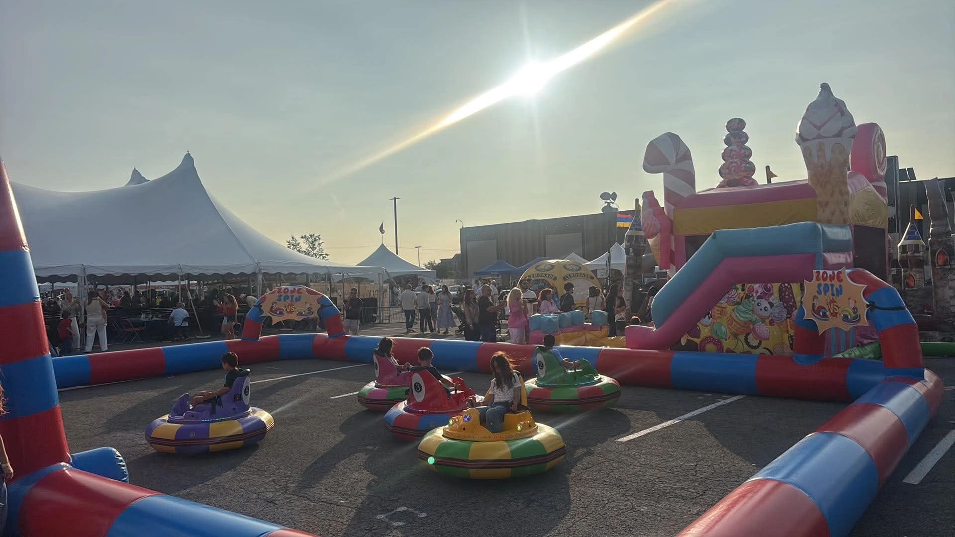 Enfants s'amusant dans des autos tamponneuses colorées à une fête en plein air.
