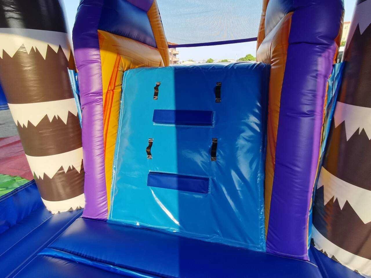 Colorful inflatable climbing wall with handles inside a bounce house.