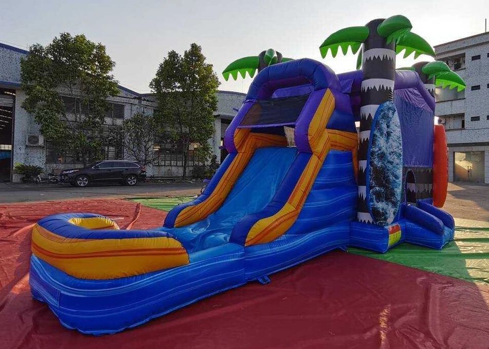 Colorful inflatable water slide with tropical palm tree decorations outdoors.