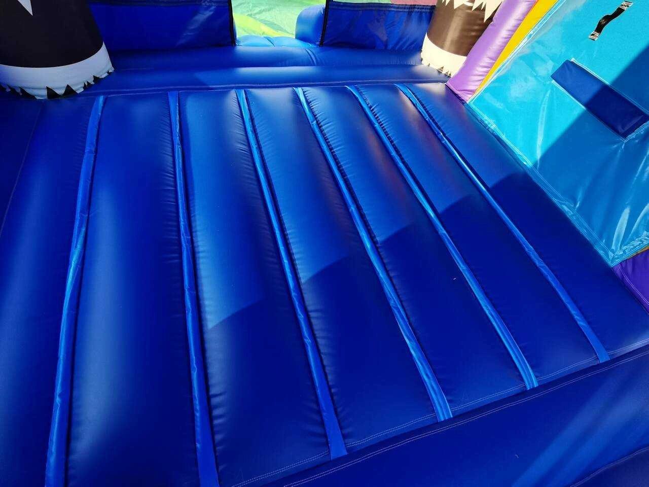Close-up of a blue inflatable bounce house floor with sunlight and shadows.