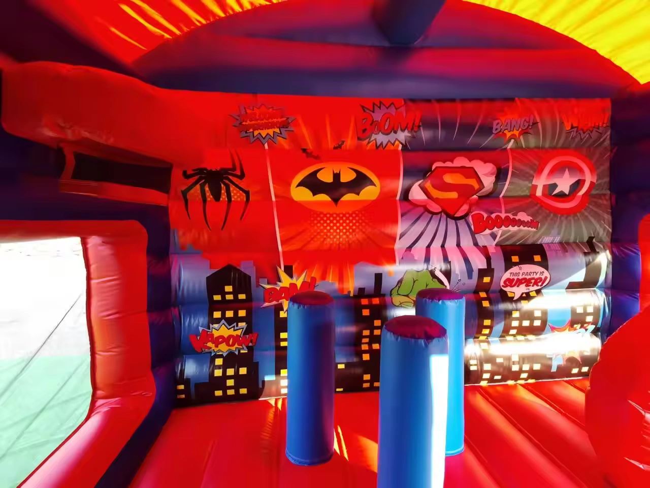 Colorful superhero-themed inflatable bounce house with comic art.