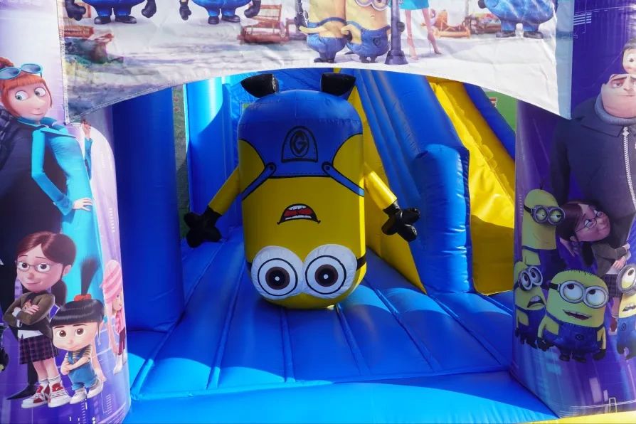 Inflatable Minion character upside down in a colorful bounce house.