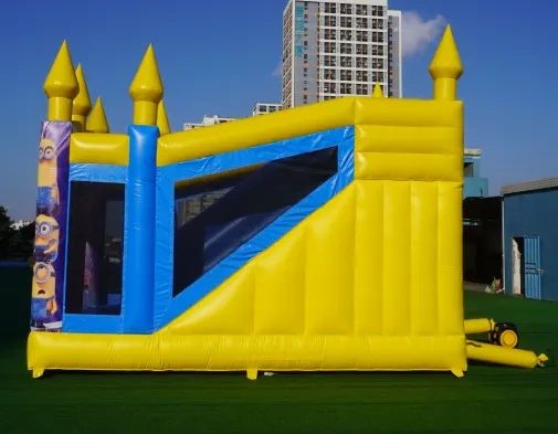 Yellow and blue inflatable bounce house with Minion decorations outdoors.
