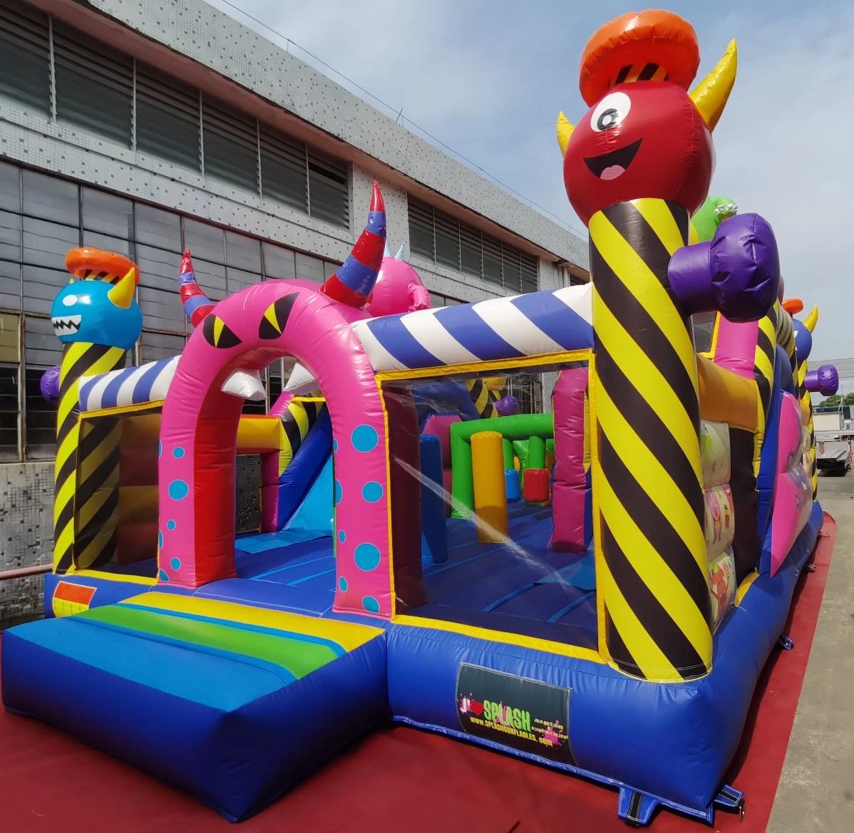 Colorful inflatable bounce house with monster-themed decorations and a blue ramp entrance.