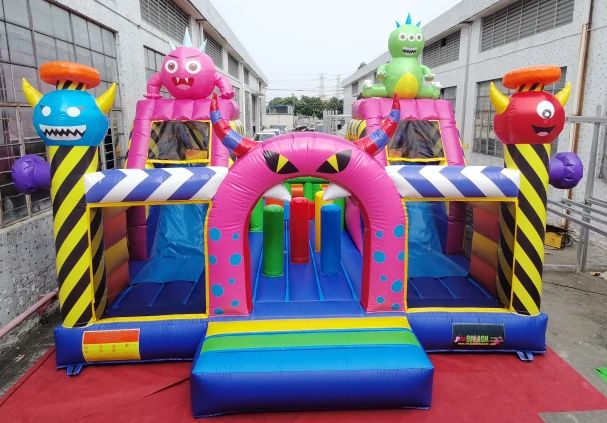 Colorful inflatable bounce house with monster designs and obstacle course.