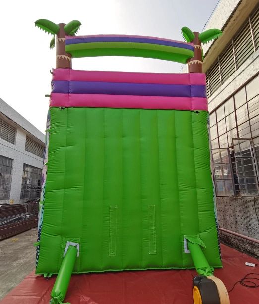 Colorful inflatable structure with palm tree decorations in an industrial outdoor setting.