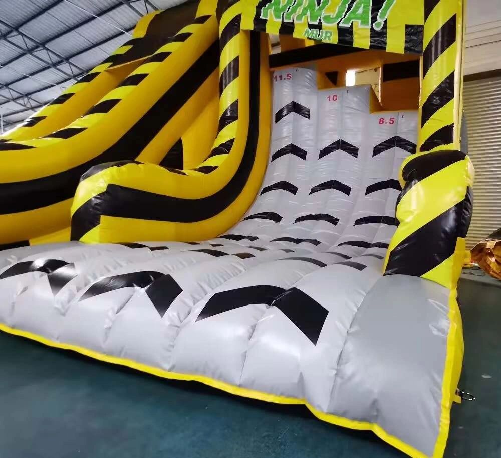 Inflatable yellow and black ninja-themed slide inside a warehouse.