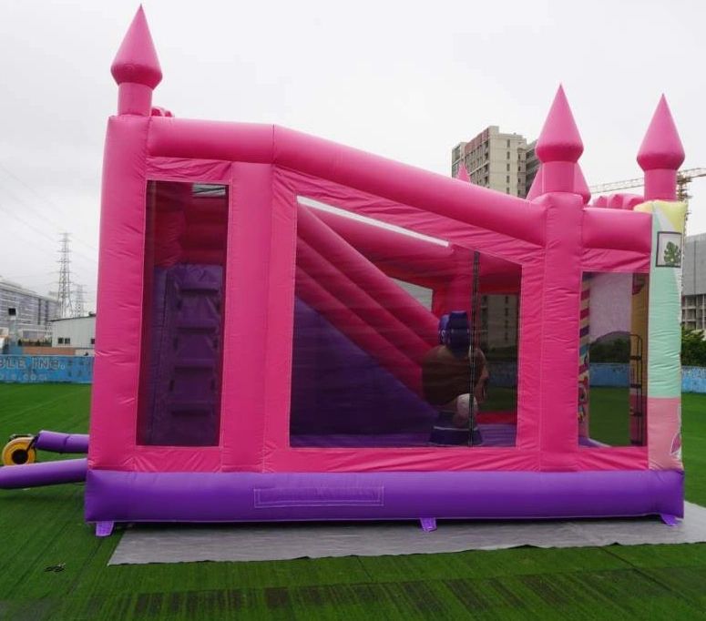 Pink and purple inflatable bounce house on grass.