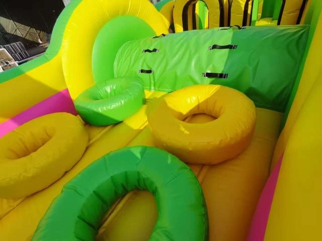 Colorful inflatable rings on a yellow and green bouncy play structure.