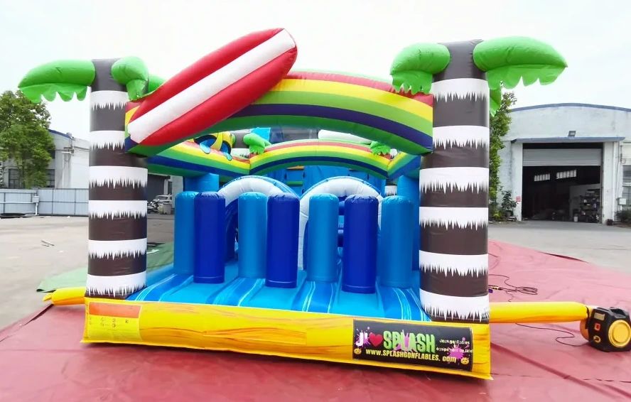 Colorful inflatable obstacle course with palm tree design and rainbow arch.
