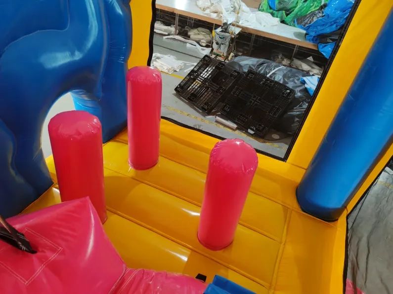 Colorful inflatable play area with red pillars and blue and yellow walls.