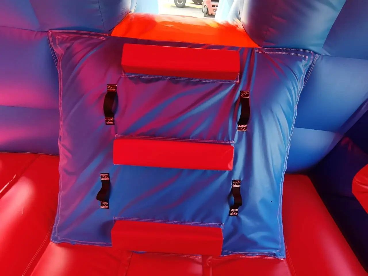 Red and blue inflatable structure with handles and padded steps.