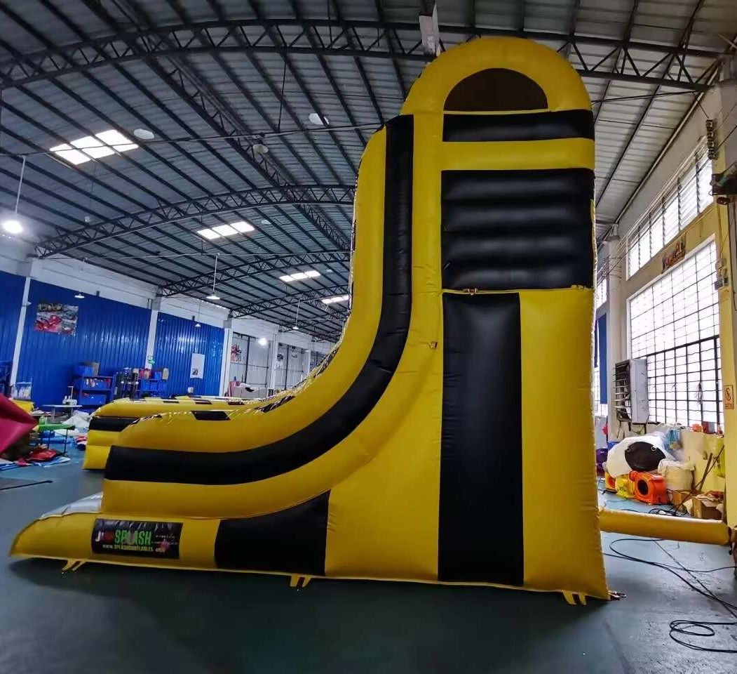 Yellow and black inflatable slide inside a warehouse.