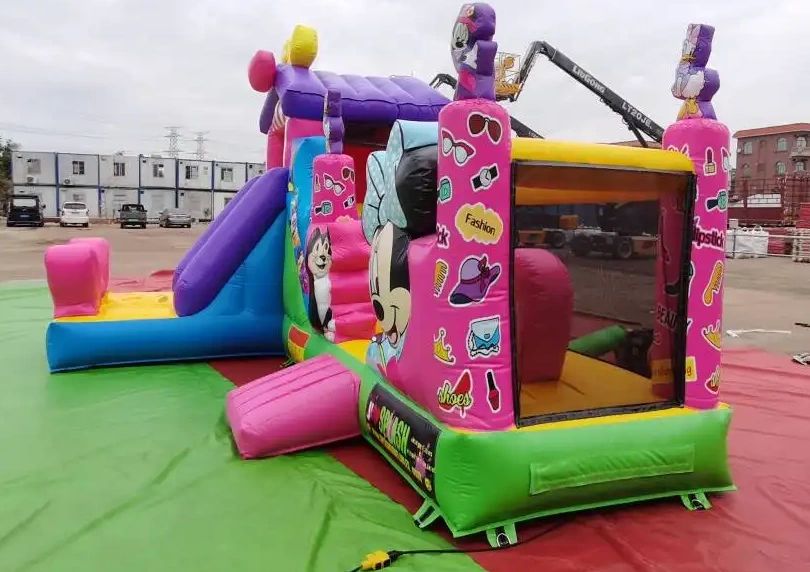 Colorful inflatable bounce house with slide and cartoon character designs.