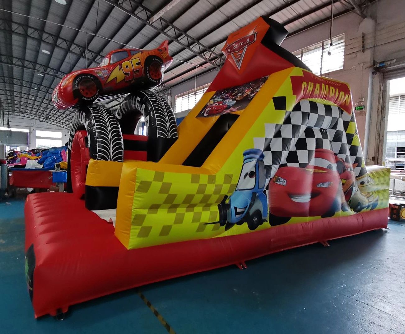 Bright inflatable Cars-themed slide with character graphics and racing tires.