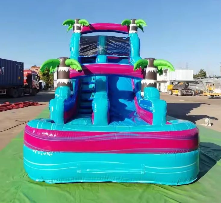 Bright inflatable water slide with palm tree decorations in an outdoor setting.