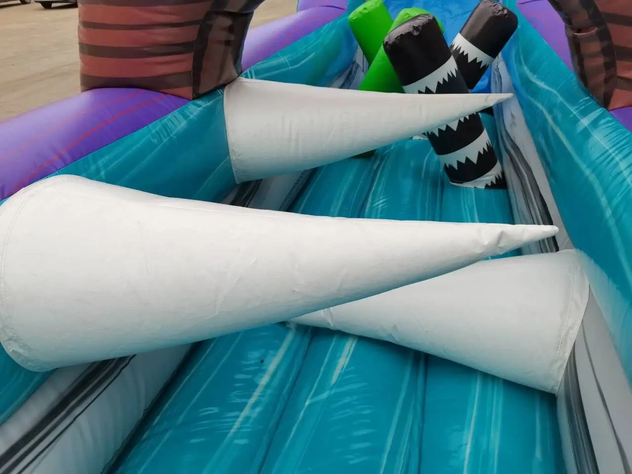 Inflatable obstacle course with white cone-shaped barriers and colorful pillars.