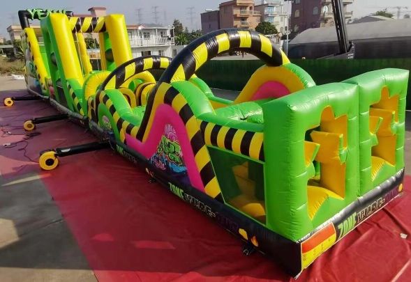 A colorful inflatable obstacle course set up outdoors on a red mat.