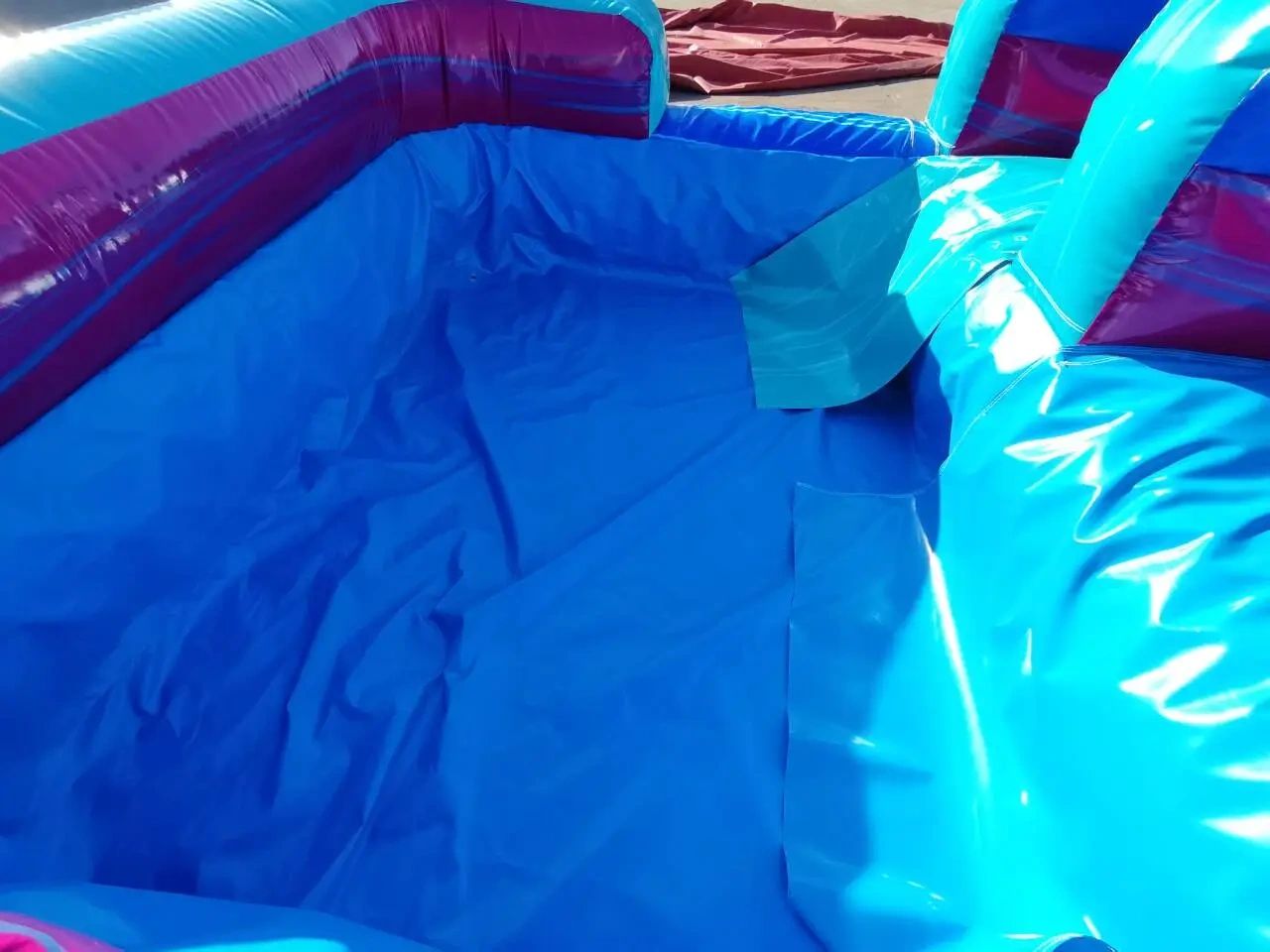 Bright blue inflatable pool with a small slide on the side.