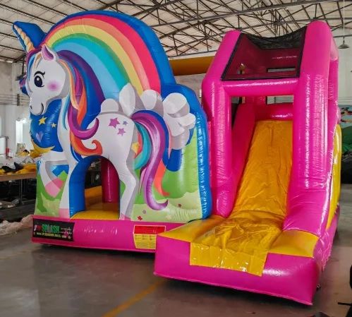 Inflatable unicorn-themed bouncy castle with a slide in vibrant colors.