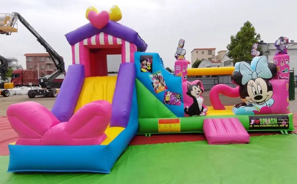 Colorful Minnie Mouse-themed inflatable bounce house and slide for kids.