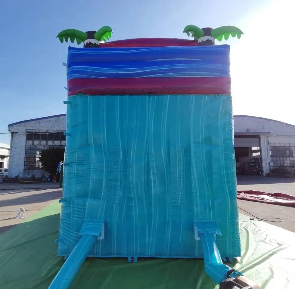 Back view of a blue inflatable water slide with palm tree decorations.