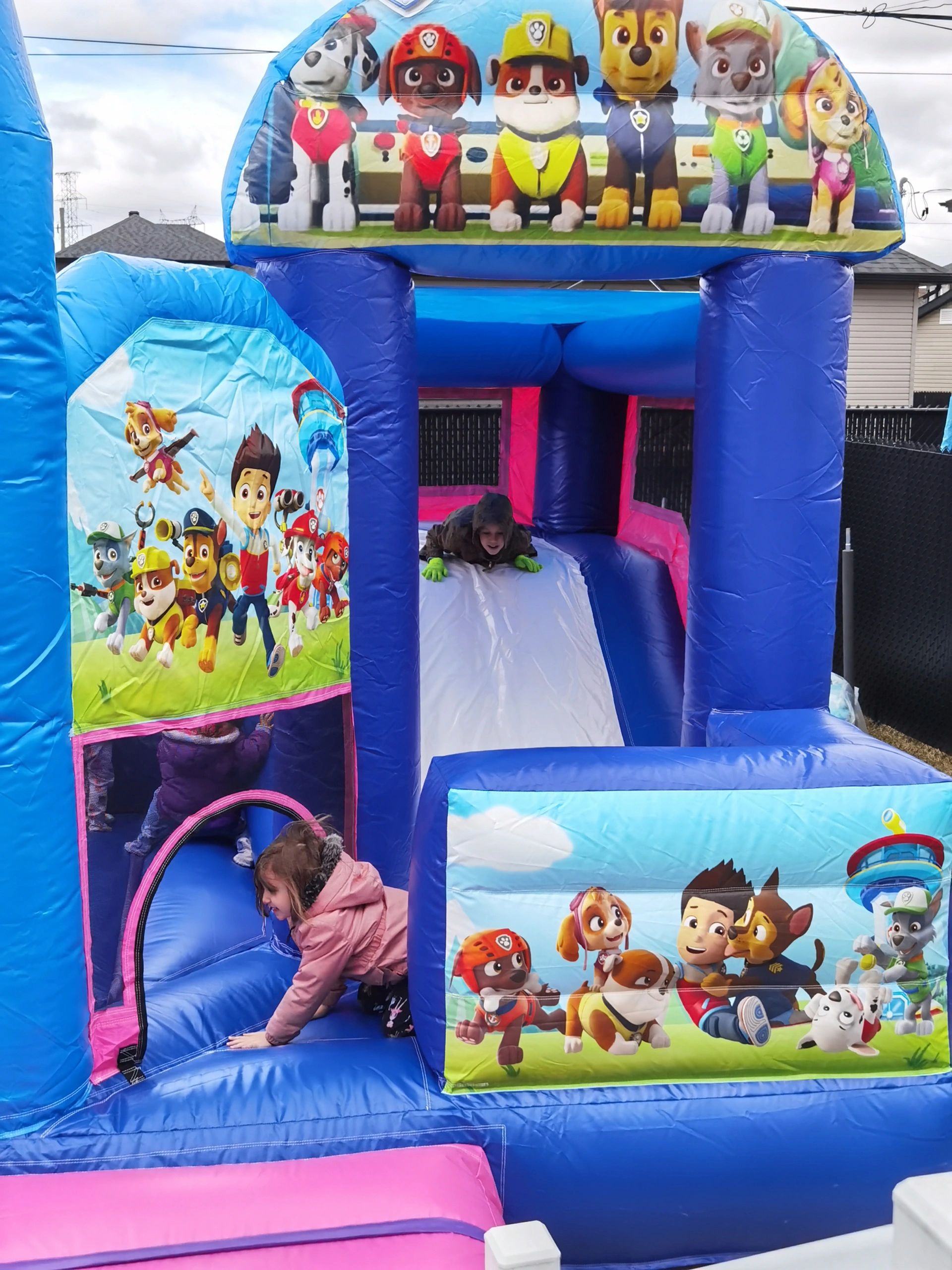 Children playing on a Paw Patrol-themed inflatable bounce house.