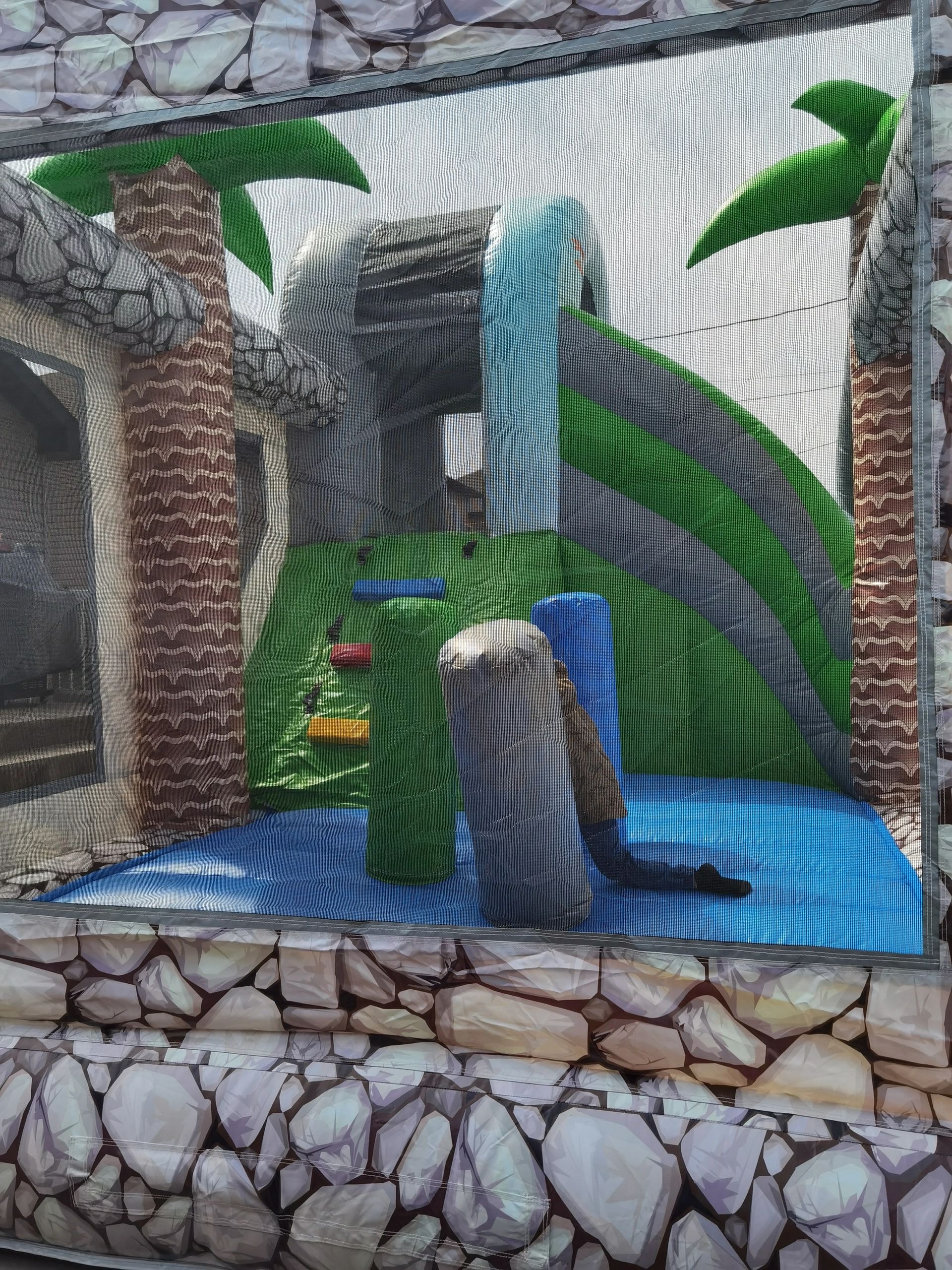 Inflatable bounce house with a tropical theme and a slide.