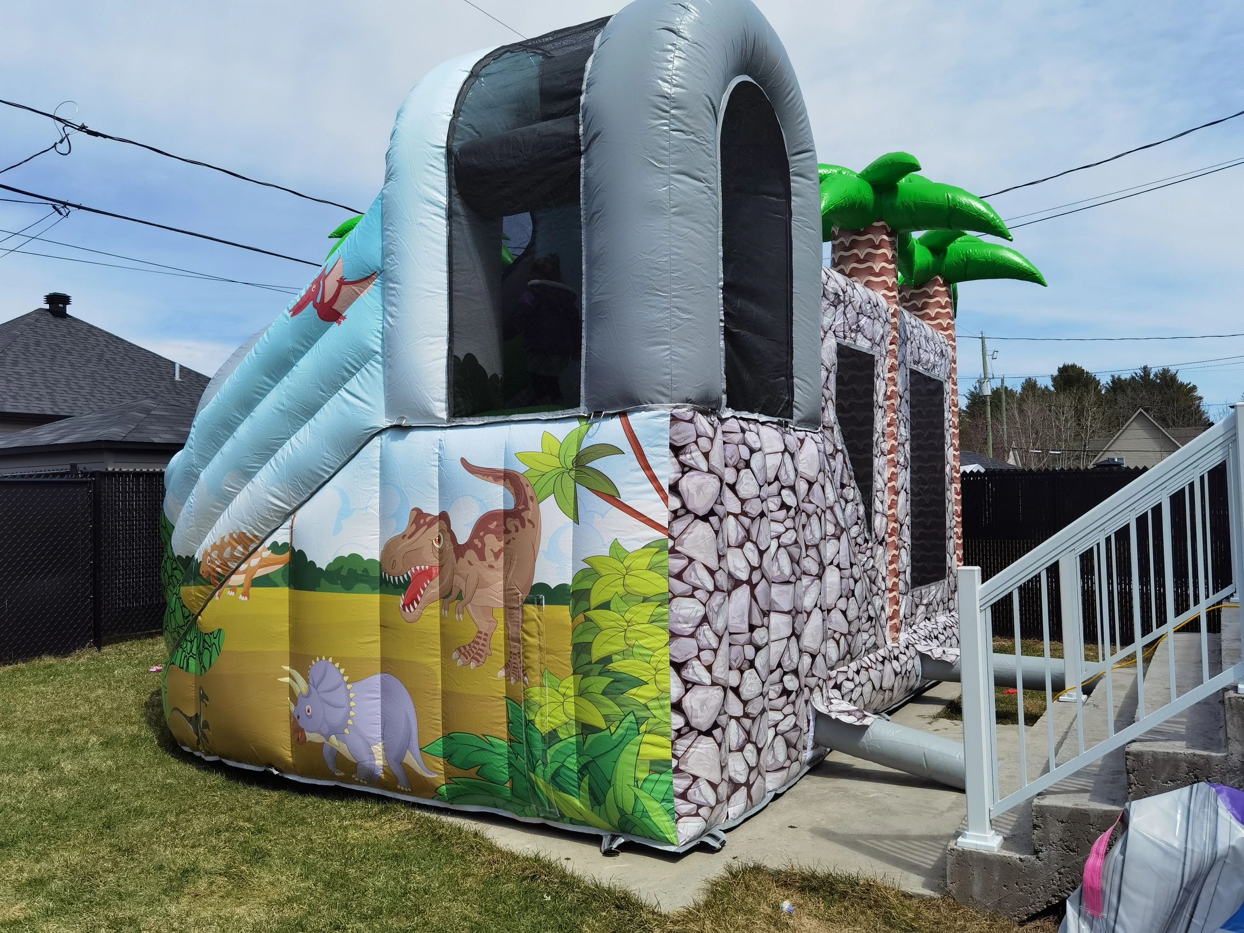 Colorful dinosaur-themed inflatable bounce house with kids inside.