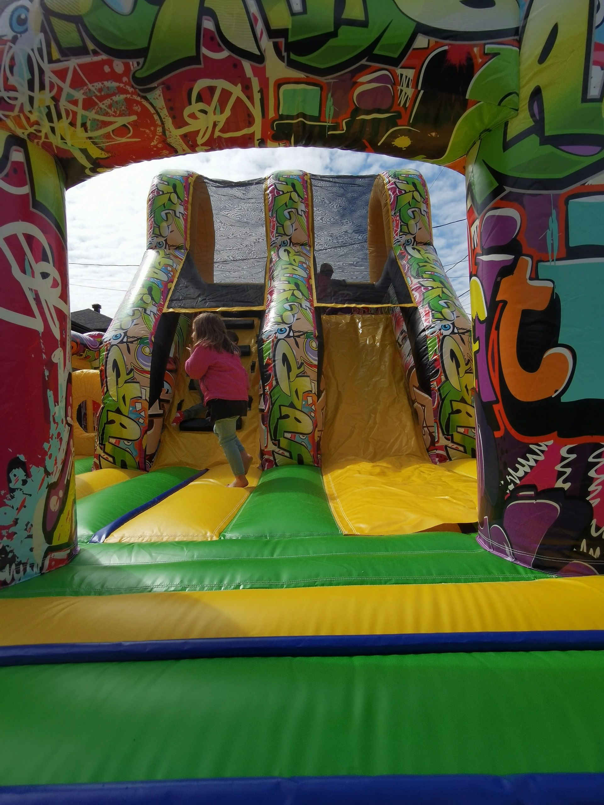 Child playing on a colorful inflatable slide with graffiti art.
