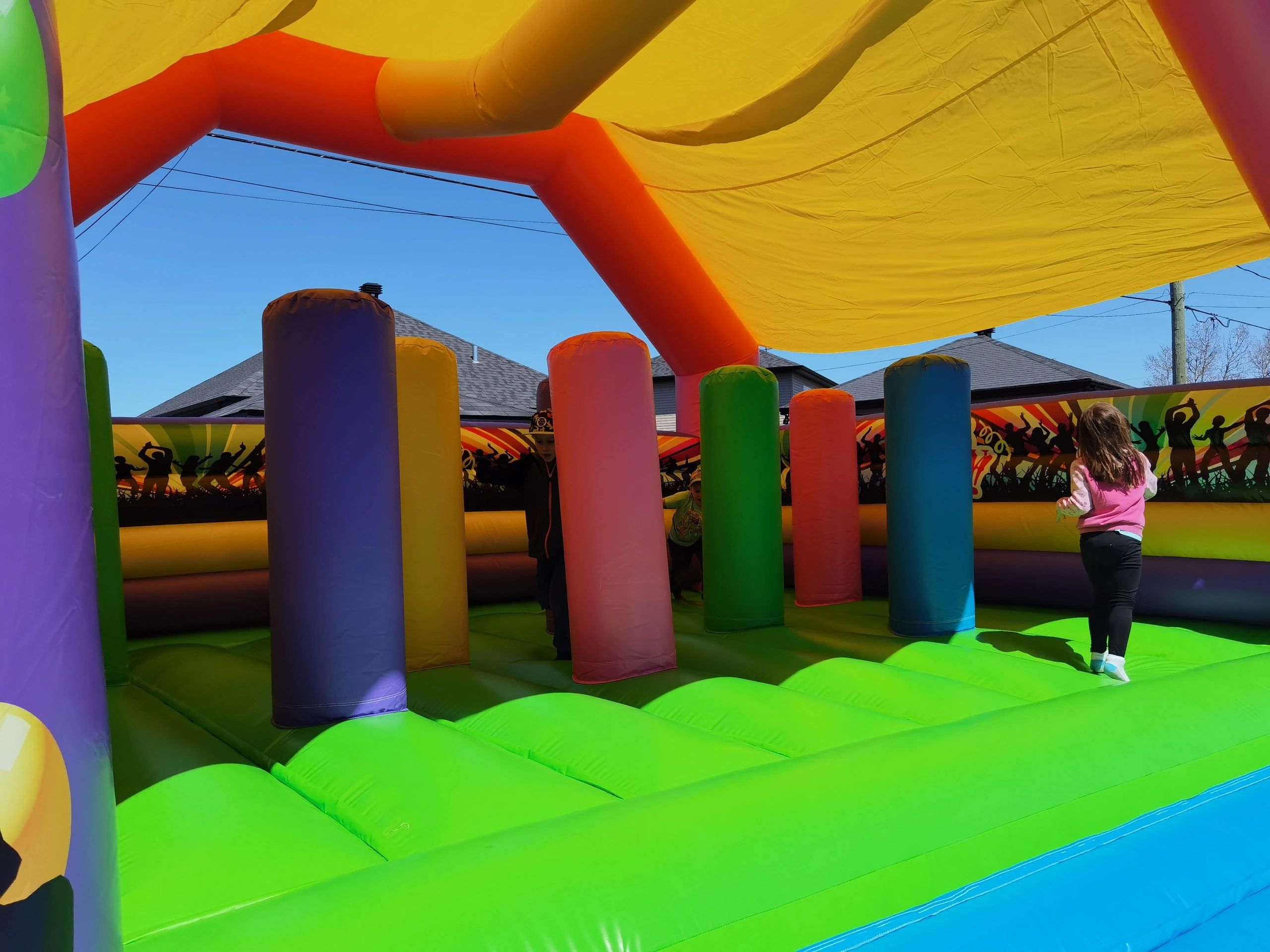 Children playing inside a colorful inflatable bounce house outdoors.