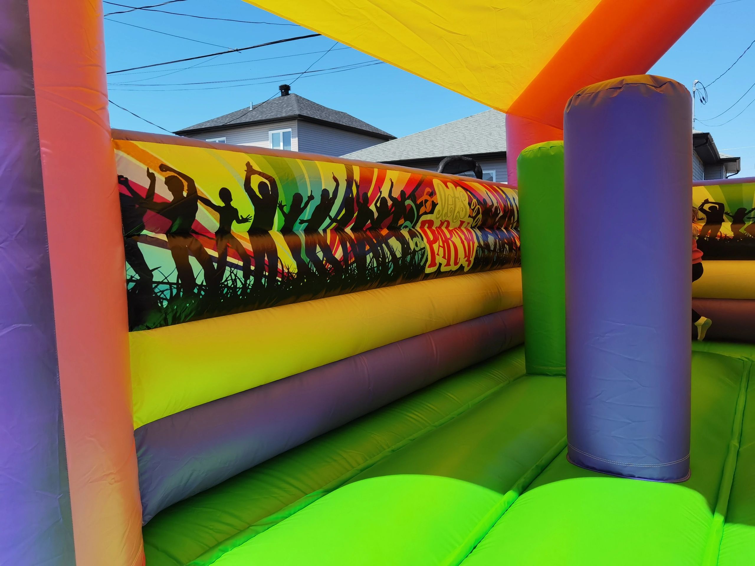 Colorful inflatable bounce house with dancing silhouettes design inside.
