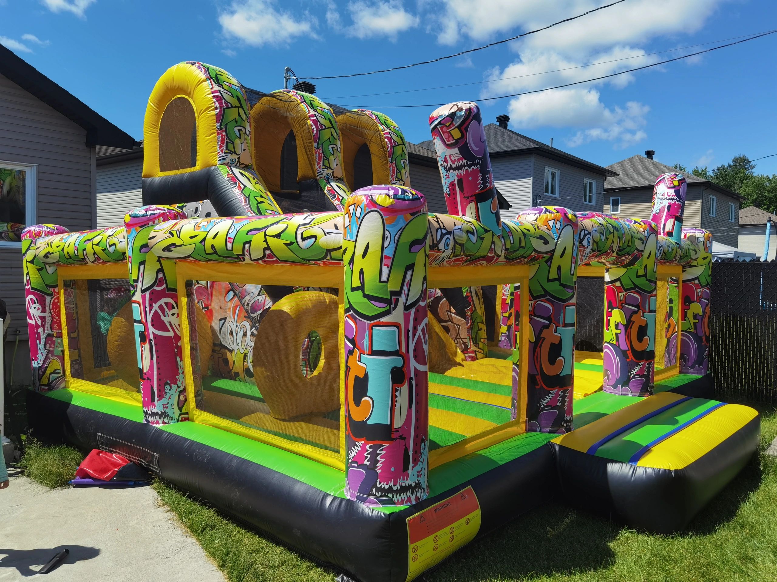 Colorful inflatable obstacle course with graffiti designs in a backyard.