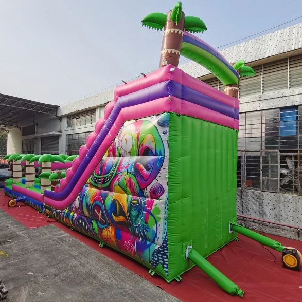 Colorful inflatable slide with tropical palm tree decorations outdoors.