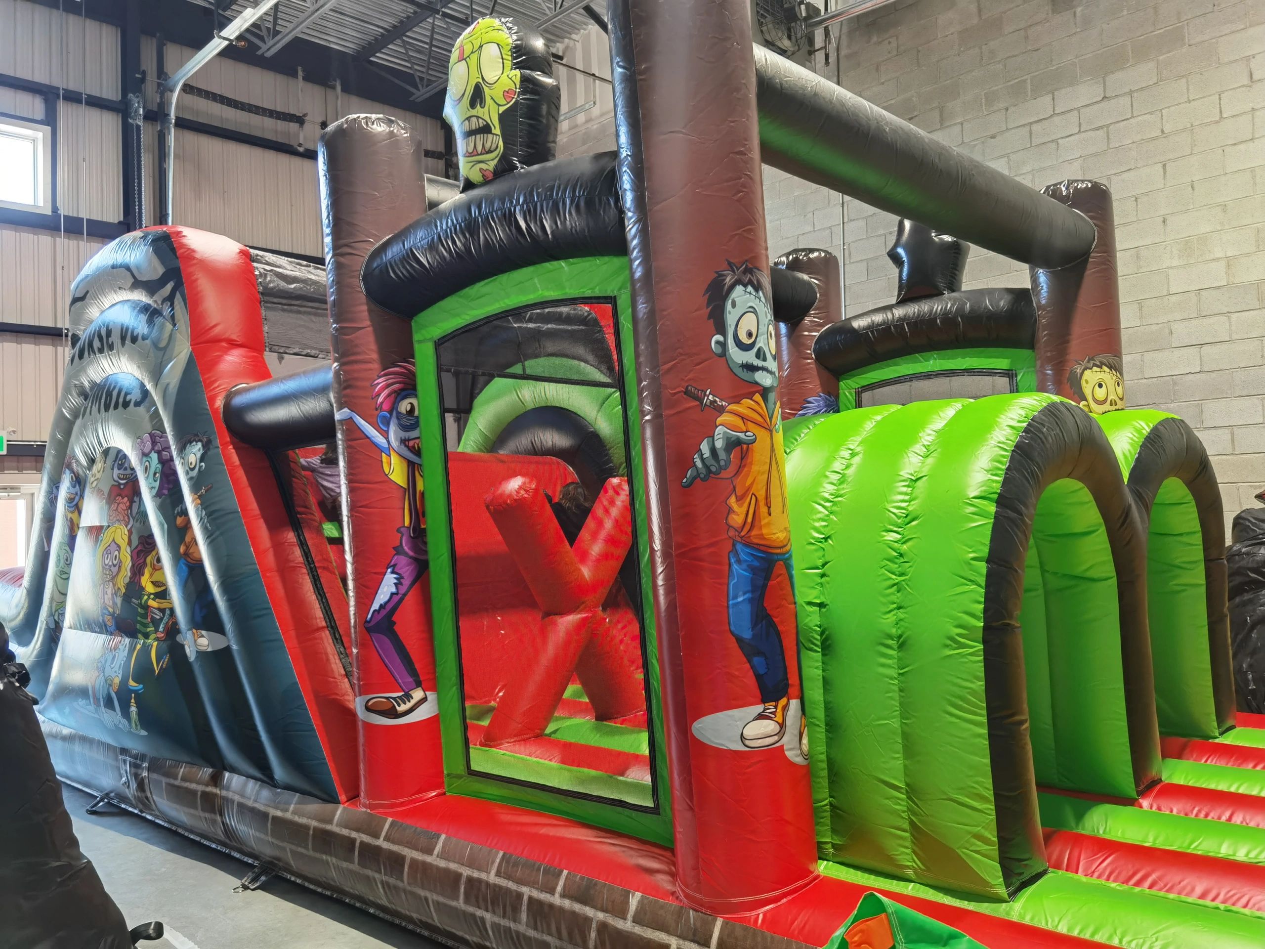 Colorful inflatable zombie-themed obstacle course indoors.
