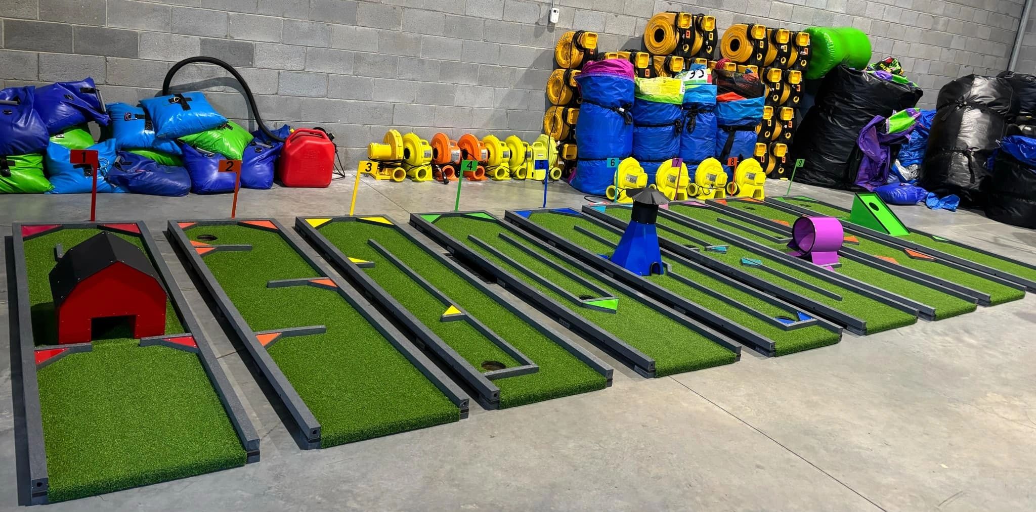 Indoor mini golf course with nine numbered holes and colorful obstacles.