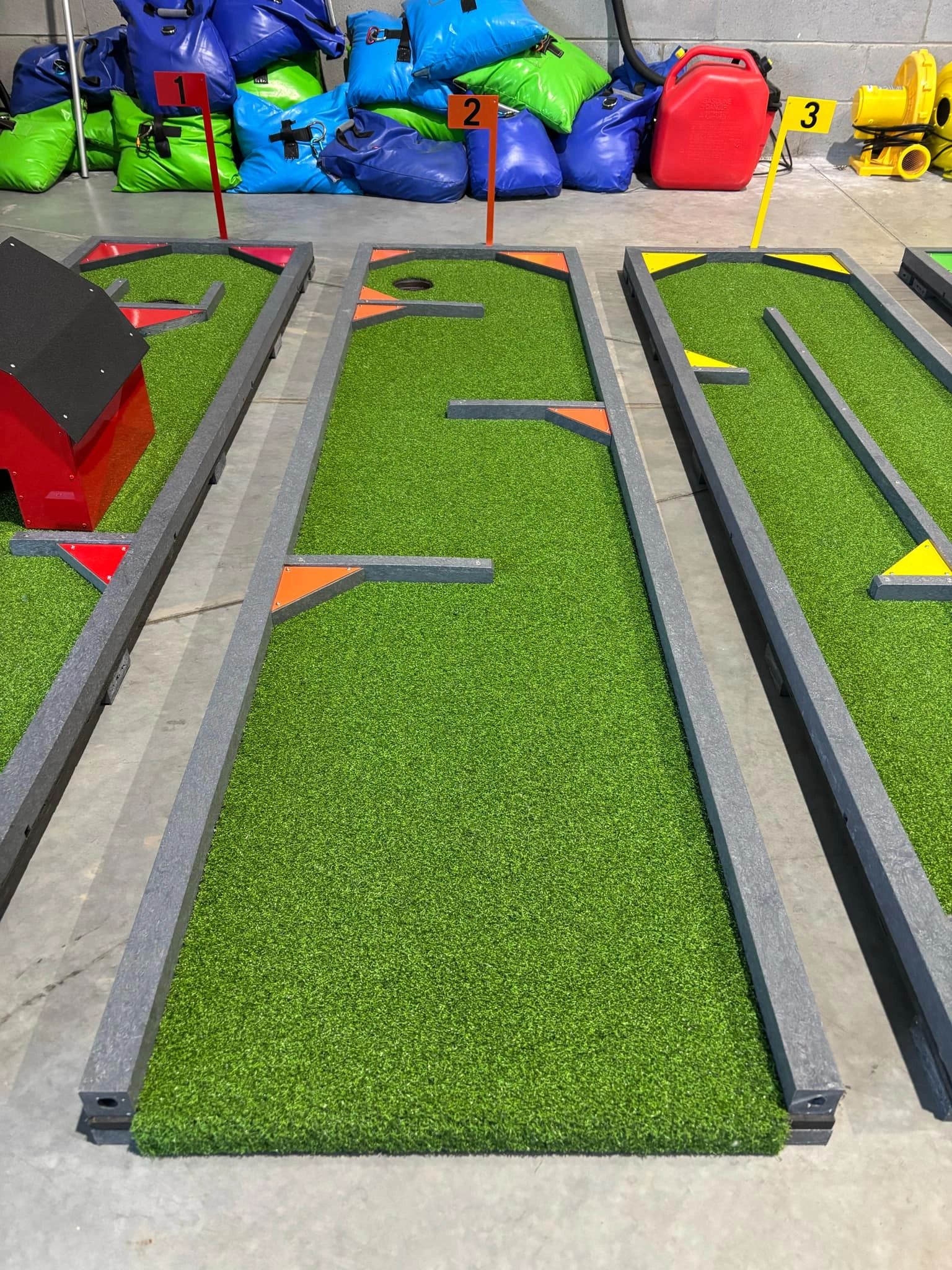 Three numbered mini golf putting greens with obstacles and colorful markers.