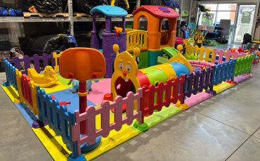 Colorful indoor playground with slides and a fenced play area for kids.