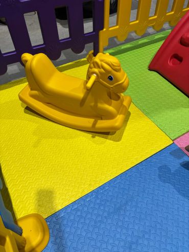 Yellow rocking horse toy on colorful foam play mats.