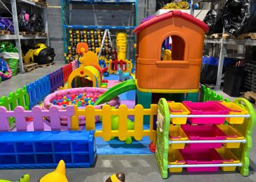 Colorful indoor play area with a plastic house, ball pit, and slide.