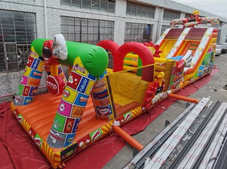 Colorful inflatable obstacle course with comic-style designs and a slide.
