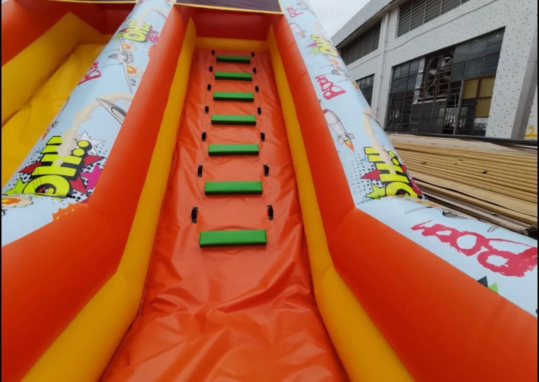 Colorful inflatable slide with green steps and comic-style decorations.
