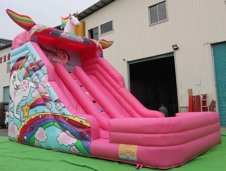 Large pink inflatable unicorn slide with rainbow and star decorations.