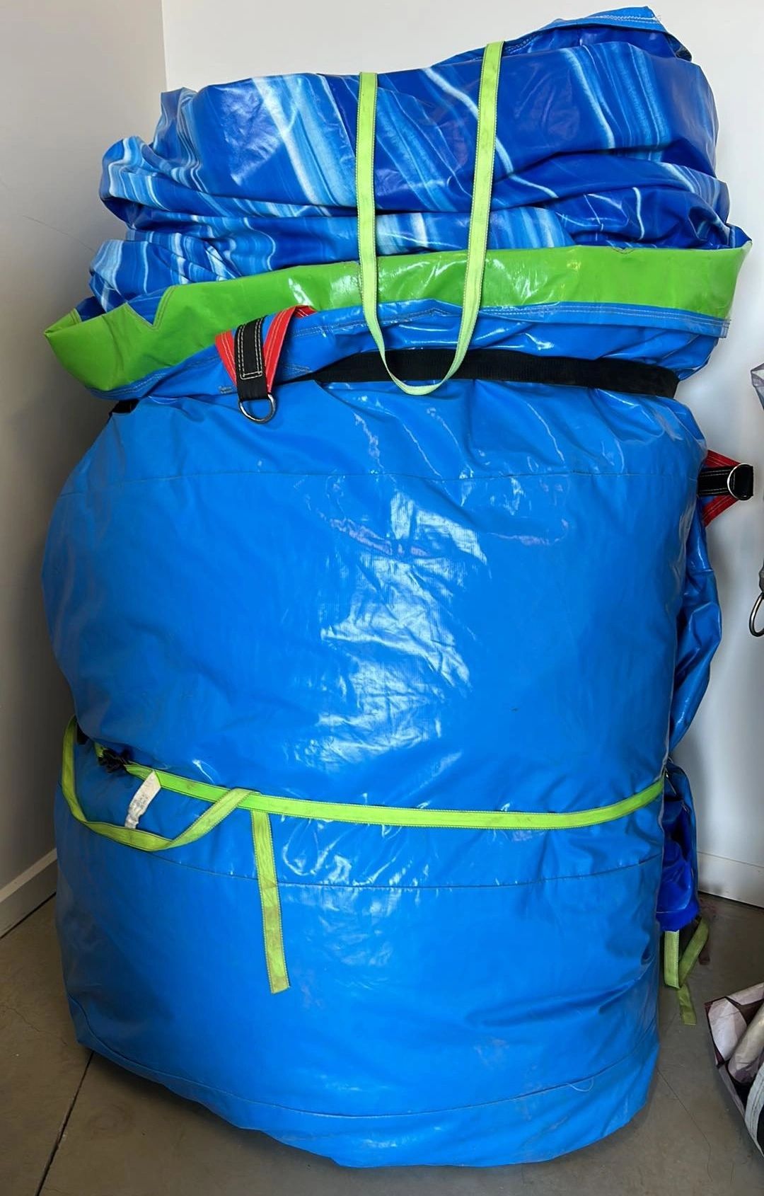 A large blue and green folded inflatable or tarp with straps.