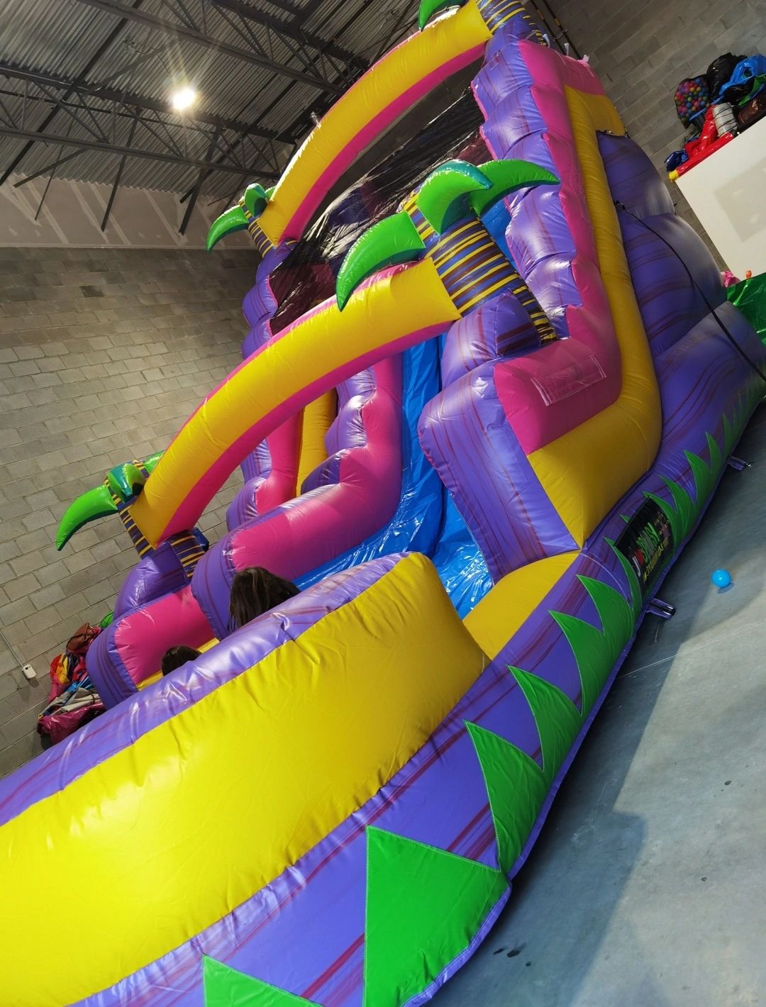 Colorful inflatable slide with palm tree designs indoors.
